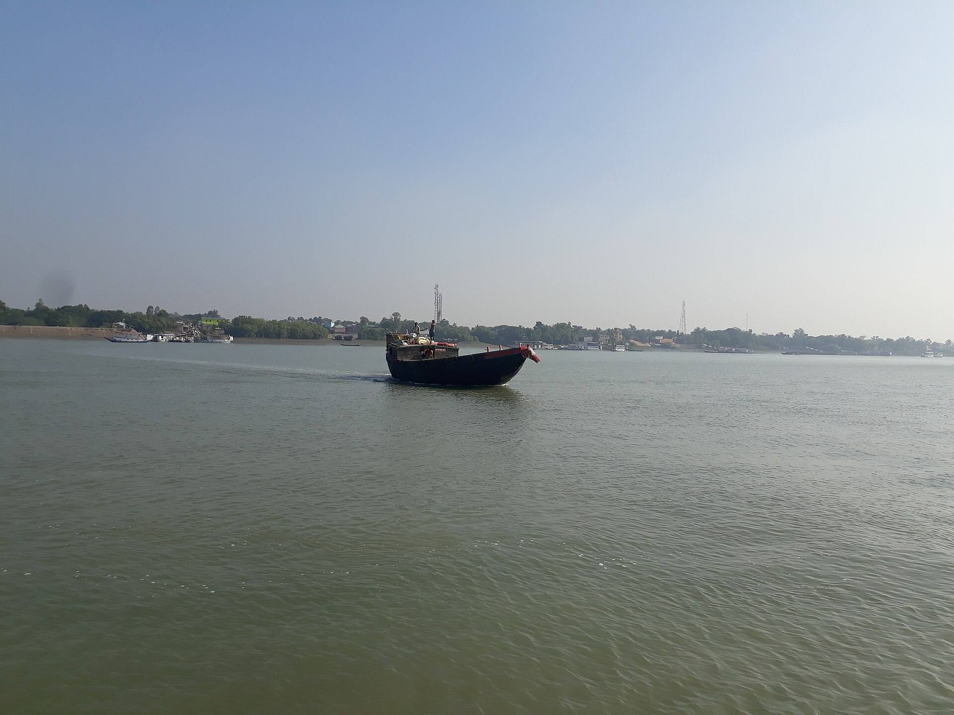A traditional wooden boat navigating a narrow forest channel in the Sundarbans.